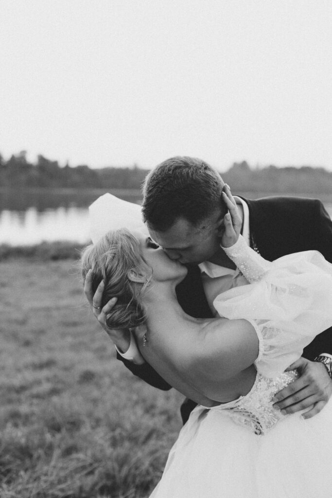 Svartvitt foto på nygift par som kyssar varandra på en äng