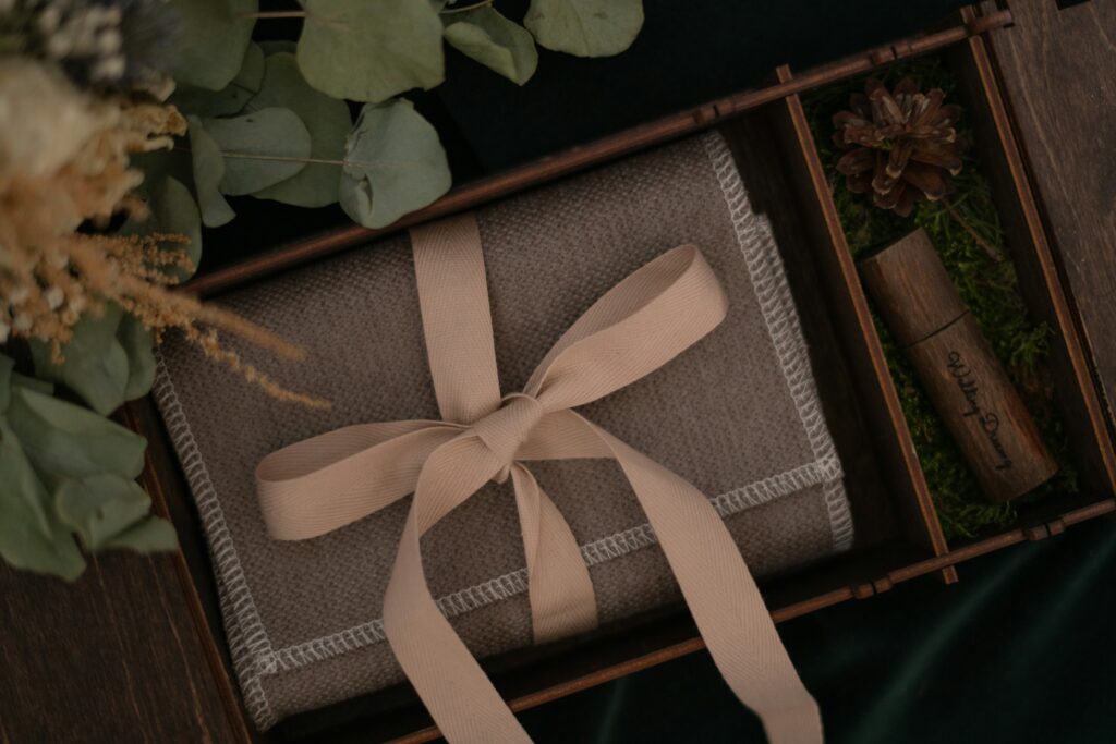 Vacker låda med bröllopspresent inslagen i brunt tyg och med rosa band.